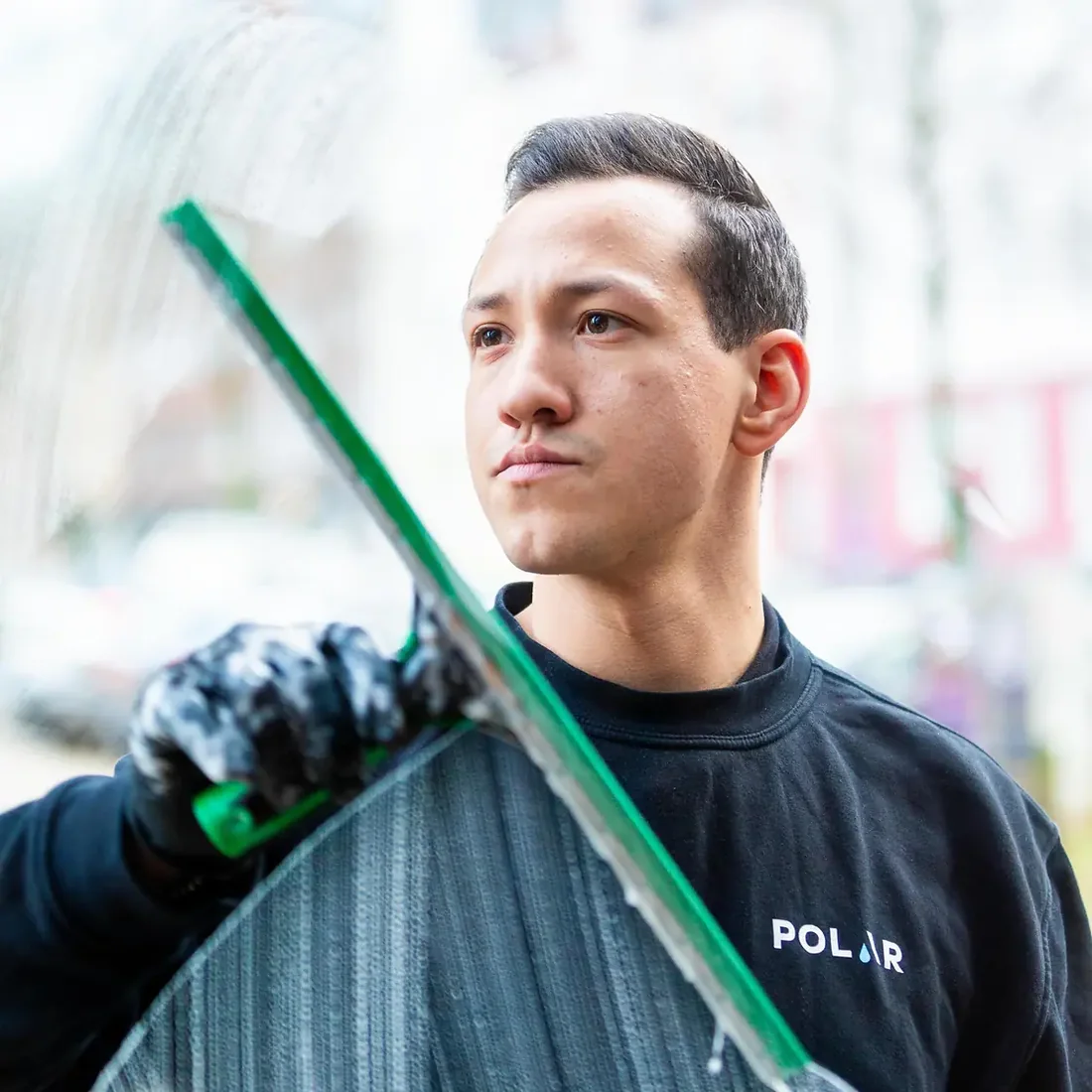 Person aus dem Polar-Team mit dem Abzieher bei der Glasreinigung in Münster