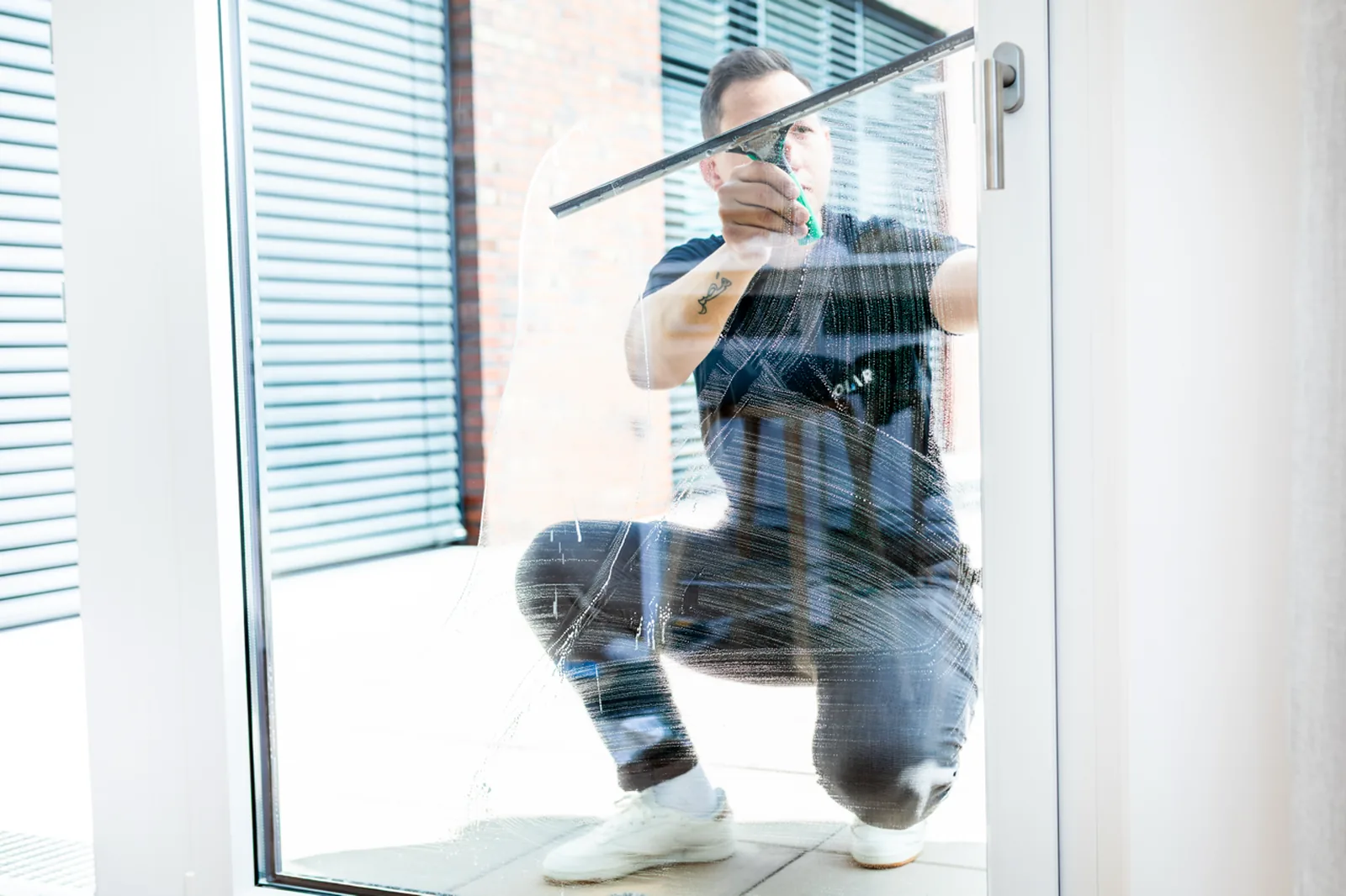 Person aus dem Polar-Team zieht bei der Glasreinigung in Münster eine Glastür streifenfrei ab